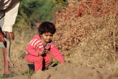 A beautiful indian child looking at the weed in the field, india, young indian child farmer in field