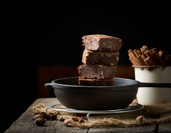 Pieces of baked brownie in a metal black frying pan on the table