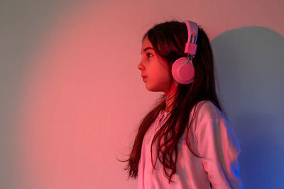 Little girl in headphones stand in neon light
