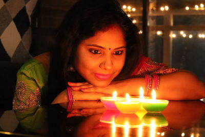 Smiling woman looking at burning diyas