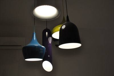 Low angle view of illuminated pendant lights against wall at home