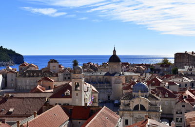 Cityscape by sea against blue sky