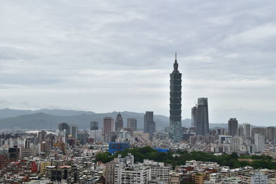 Buildings in city against cloudy sky