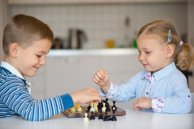 Cute sibling playing chess at home