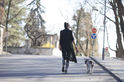 Woman with dog standing against tree