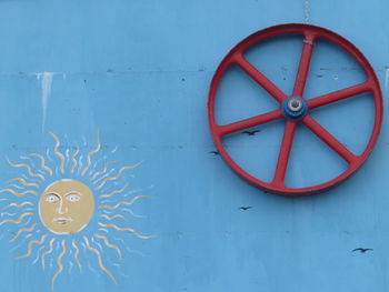 Red wheel hanging from blue wall
