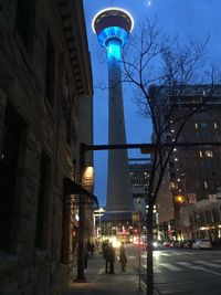 Illuminated street light in city against sky at night