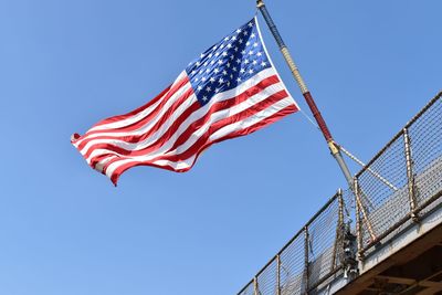 Low angle view of american flag on bridge against clear blue sky