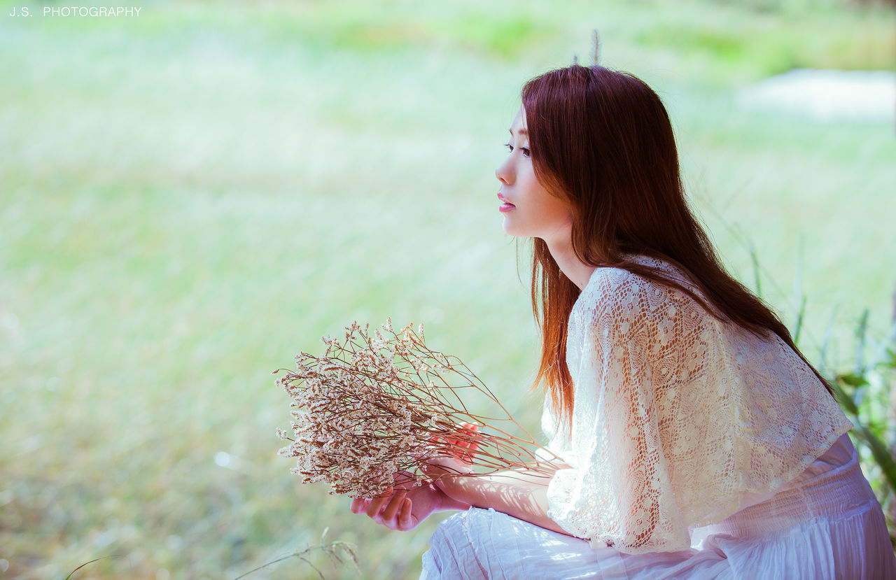 focus on foreground, lifestyles, young adult, leisure activity, young women, long hair, person, casual clothing, side view, standing, field, waist up, looking away, outdoors, day, flower, headshot, nature