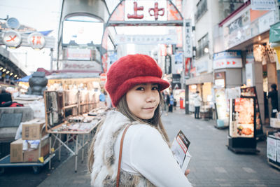 Portrait of young woman standing on street in city