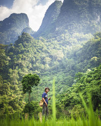 Man standing on land against tree mountains