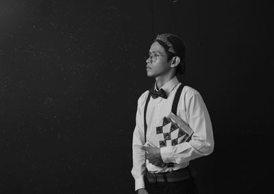 Man with book standing against black background