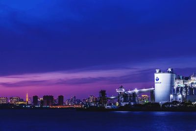 Illuminated buildings in city against blue sky