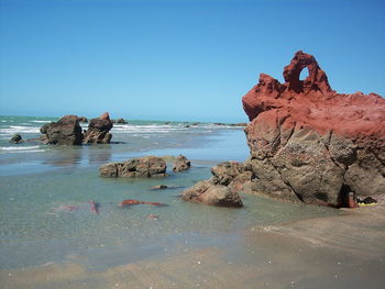 Scenic view of rocks in sea against clear blue sky