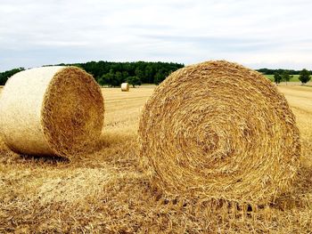 Hay bales on field against sky