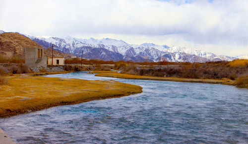 Scenic view of lake by snowcapped mountains against sky