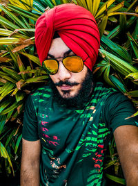 Portrait of young man wearing turban and sunglasses against plants