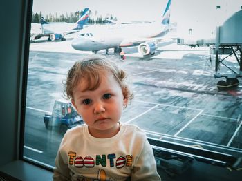 Portrait of cute girl at airport terminal against window
