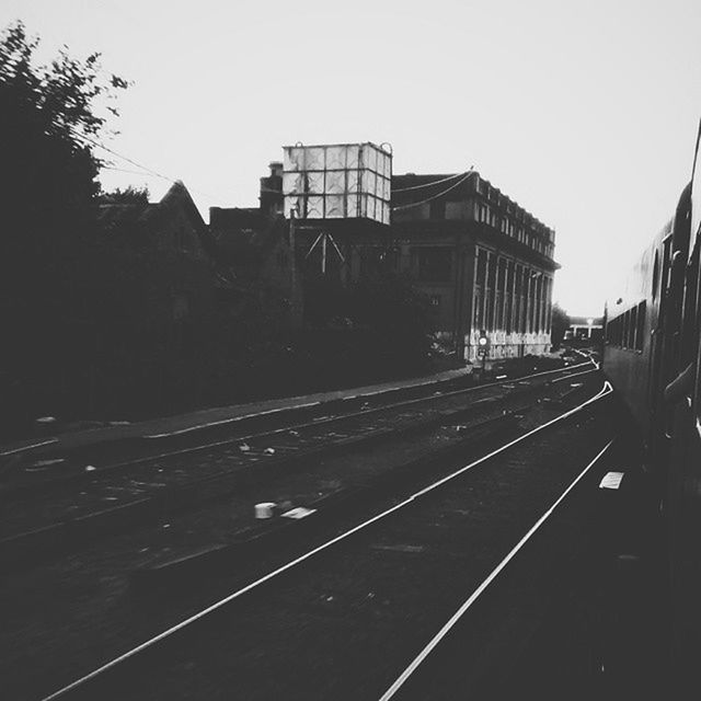 building exterior, architecture, built structure, clear sky, railroad track, transportation, rail transportation, public transportation, city, sky, railroad station, copy space, outdoors, building, day, railroad station platform, residential building, no people, residential structure, train - vehicle