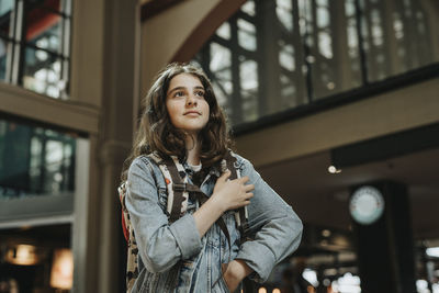 Low angle view of girl looking away while standing at railroad station