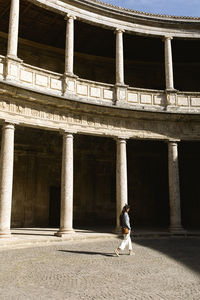 A young woman walks at the courtyard of the charles v palace, granada