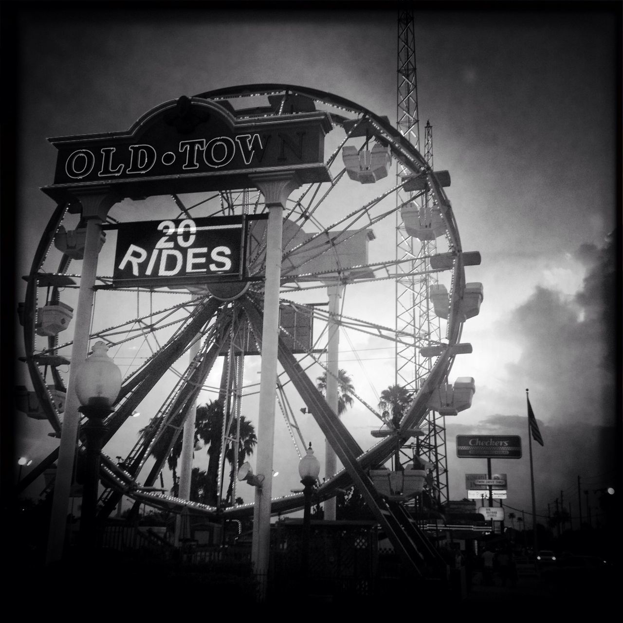 transfer print, low angle view, built structure, sky, architecture, auto post production filter, communication, building exterior, arts culture and entertainment, amusement park, ferris wheel, outdoors, dusk, amusement park ride, cloud - sky, text, no people, day, silhouette, cloud