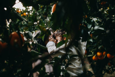 Mother and daughter embracing seen through plant outdoors