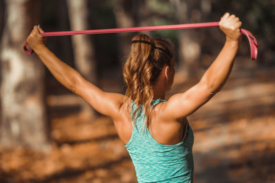 Rear view of female athlete exercising with resistance band at park