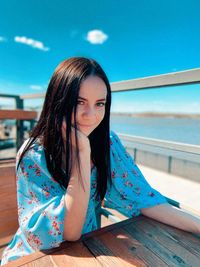 Portrait of young woman sitting on railing