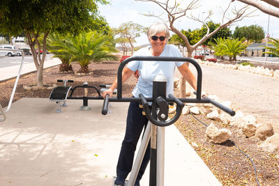 Portrait of senior woman exercising on exercise machine at park