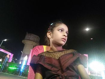 Low angle view of girl looking away at night