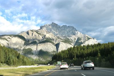 Cars on road by mountain against sky