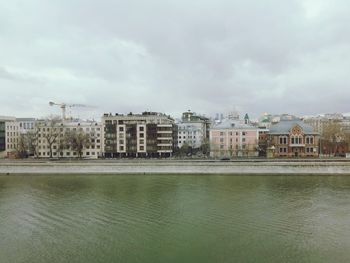 Buildings by river against sky in city