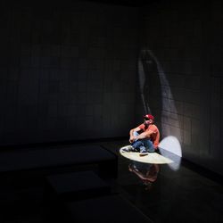 High angle view of man looking away while sitting against wall in building