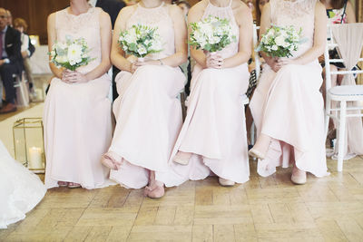 Low section of bridesmaids sitting on chairs