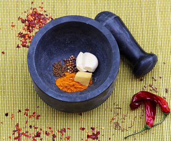 High angle view of various ingredients in mortar by pestle on mat