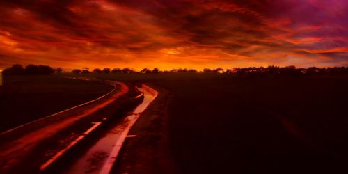 Scenic view of road against dramatic sky during sunset