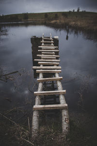 View of old footbridge in lake against sky