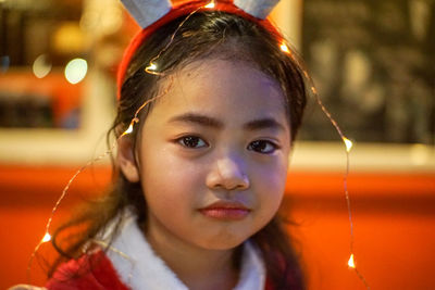 Close-up portrait of cute girl with string lights