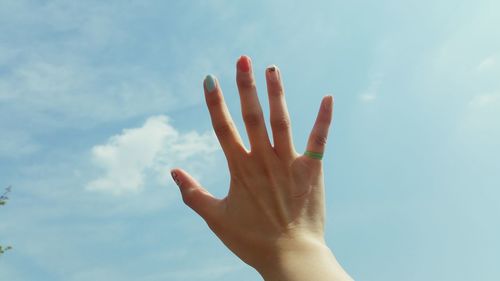 Cropped hand of woman against sky