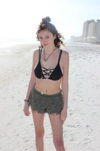 Young woman standing on beach against sky