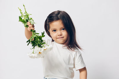 Portrait of young woman holding flowers against white background