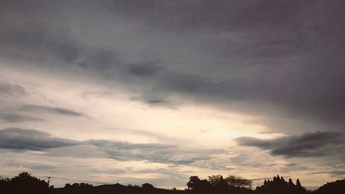 Low angle view of silhouette trees against dramatic sky