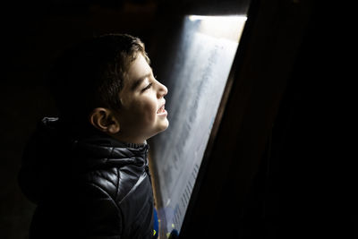 Little boy reading a poster at night