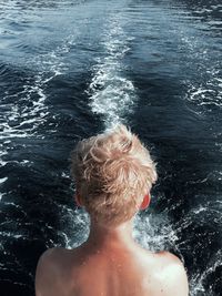 Rear view of shirtless boy swimming in sea