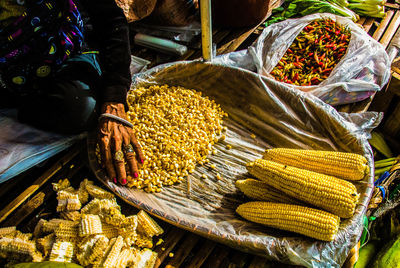 High angle view of woman selling sweetcorns at market stall