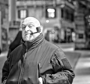 Portrait of bald man smoking pipe in city