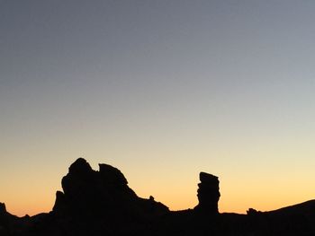 Low angle view of silhouette rocks against clear sky