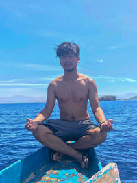Portrait of young man sitting against sea