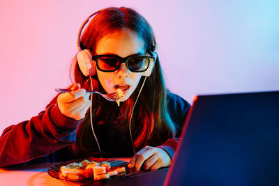 Girl wearing headphones and sunglasses eating food